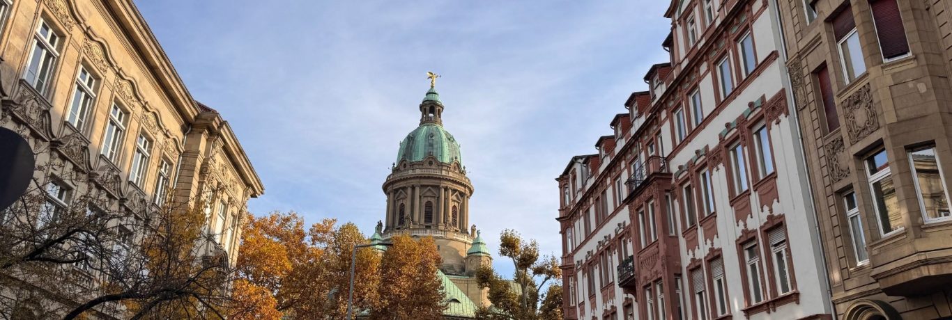 Mannheim Wasserturm Brunnen in einem parkähnlichen Platz mit klassischen Gebäuden und Bäumen im Hintergrund.